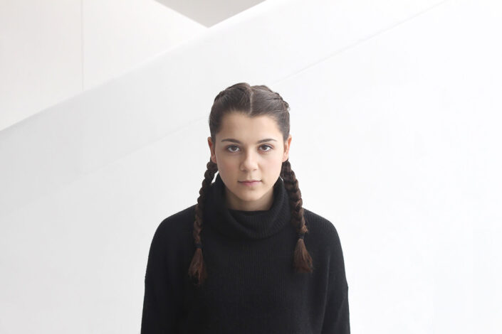Portrait of girl in pony tail in front of white wall
